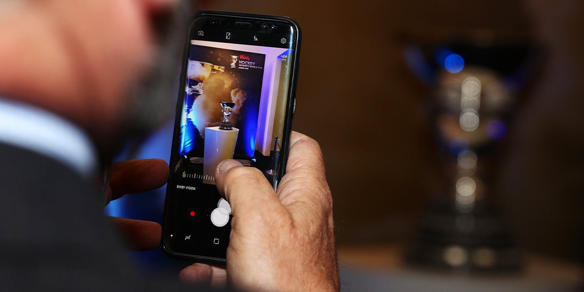 Someone taking a picture of someone taking a picture of the Womens World Cup Trophy 