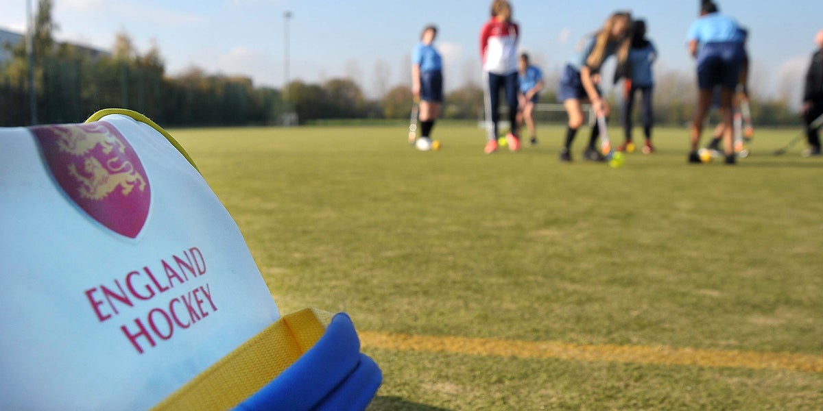 England Hockey logo on a bag with hockey being played in the background 