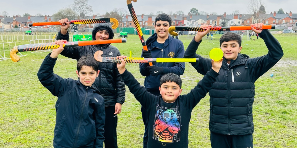 Boys holding hockey sticks and smiling