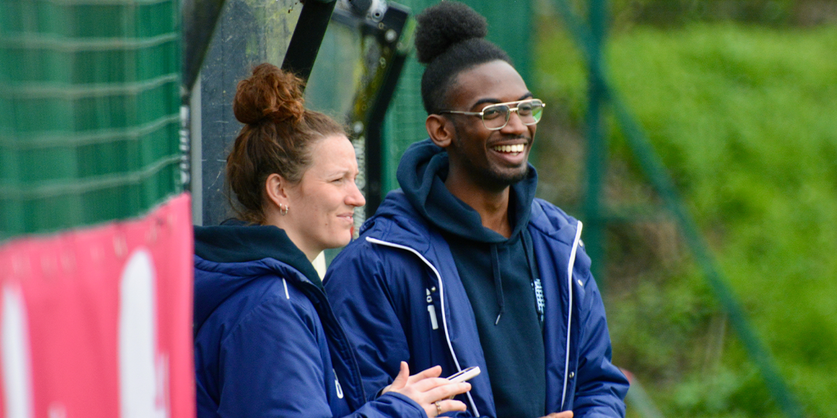 male and female coaches talking at the side of the pitch 
